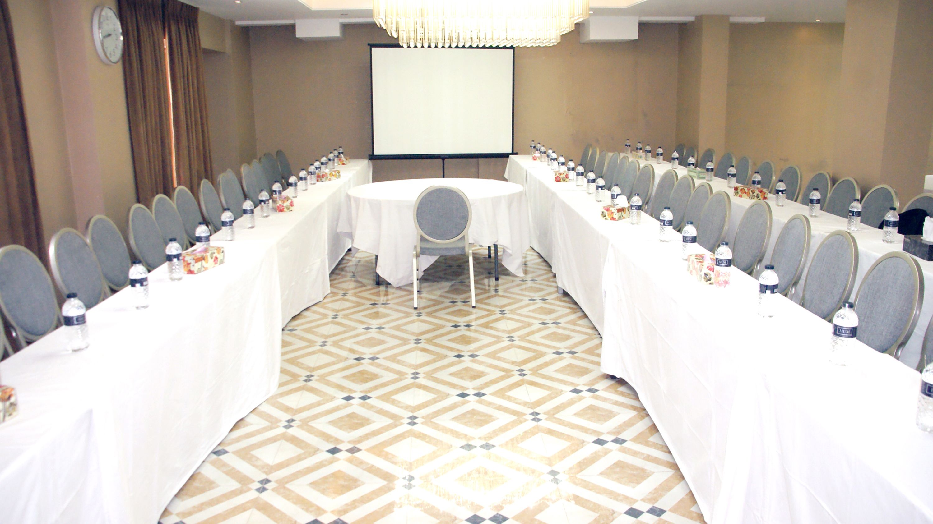 A conference room with a long table, chairs, and a projector screen.