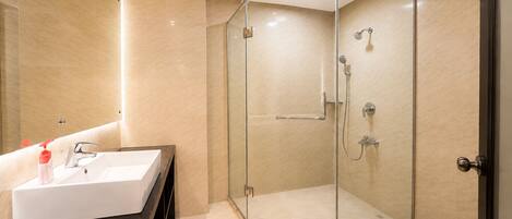 Un baño moderno con ducha de vidrio, un lavabo blanco y un mueble de tocador negro.