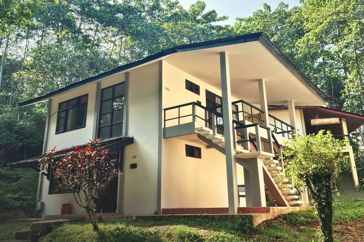 Un bâtiment à deux étages doté d’un porche couvert, d’un escalier et d’un petit jardin.