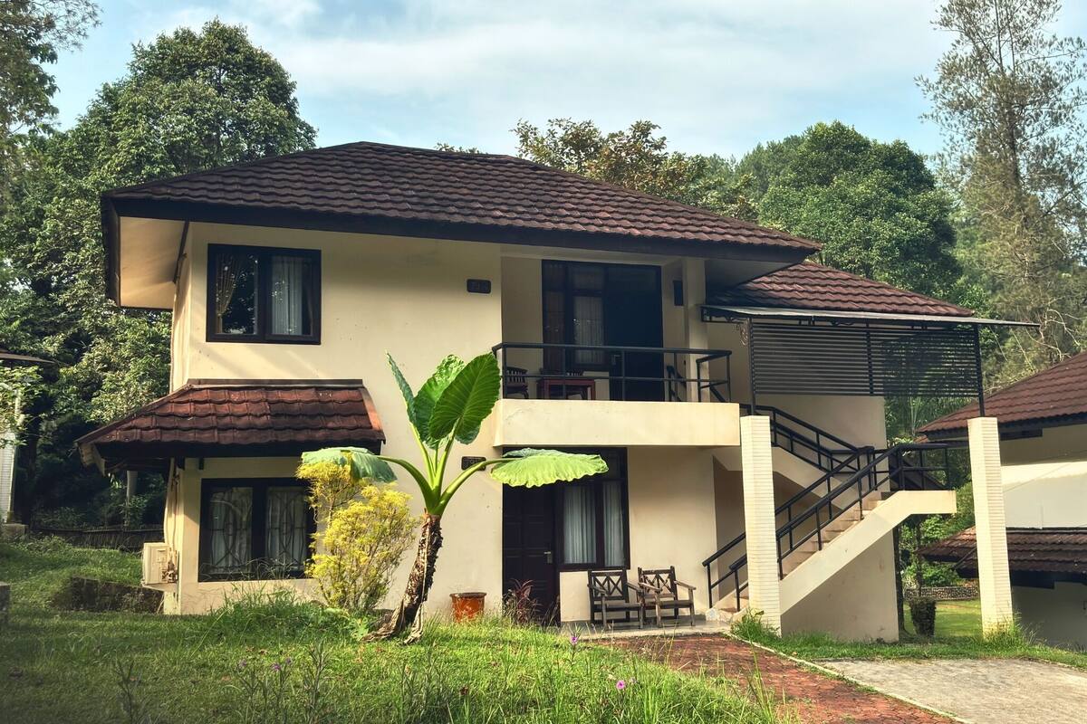 Une maison à deux étages avec un balcon, un escalier et un jardin.