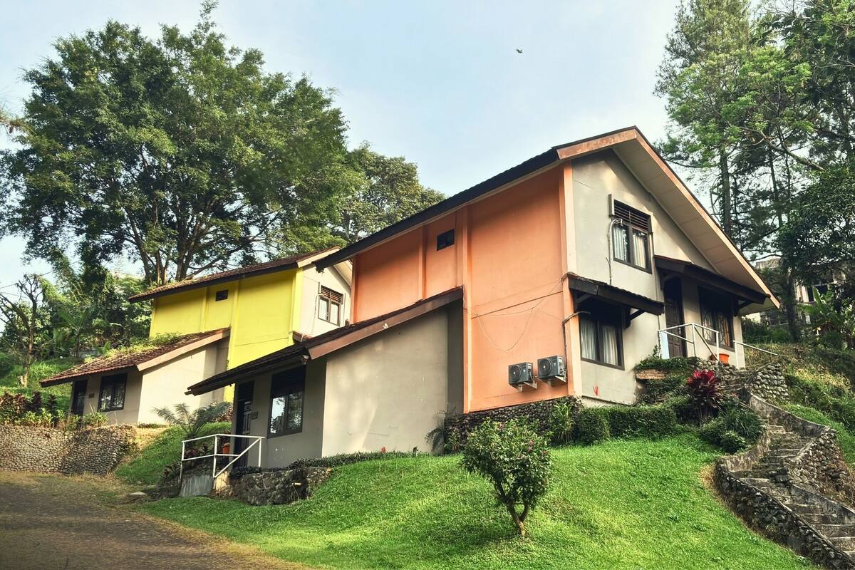 Une maison à deux étages, dotée d’un toit en pente, d’un petit porche et d’un escalier en pierre menant à l’entrée.