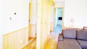 A hallway with wooden flooring and a grey sofa.