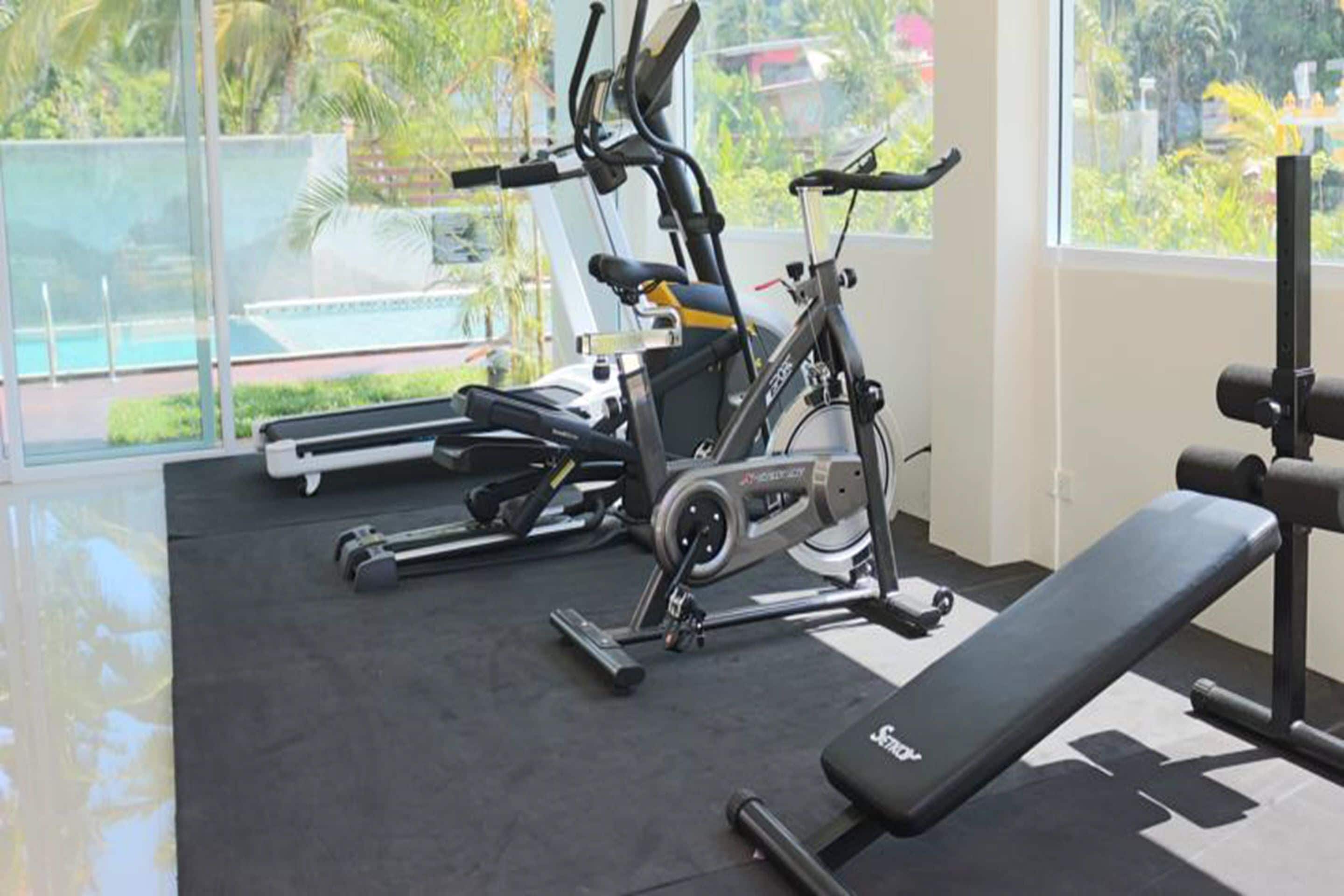 Un gimnasio con equipo de ejercicio, incluyendo una cinta de correr, una bicicleta estática y una banca.