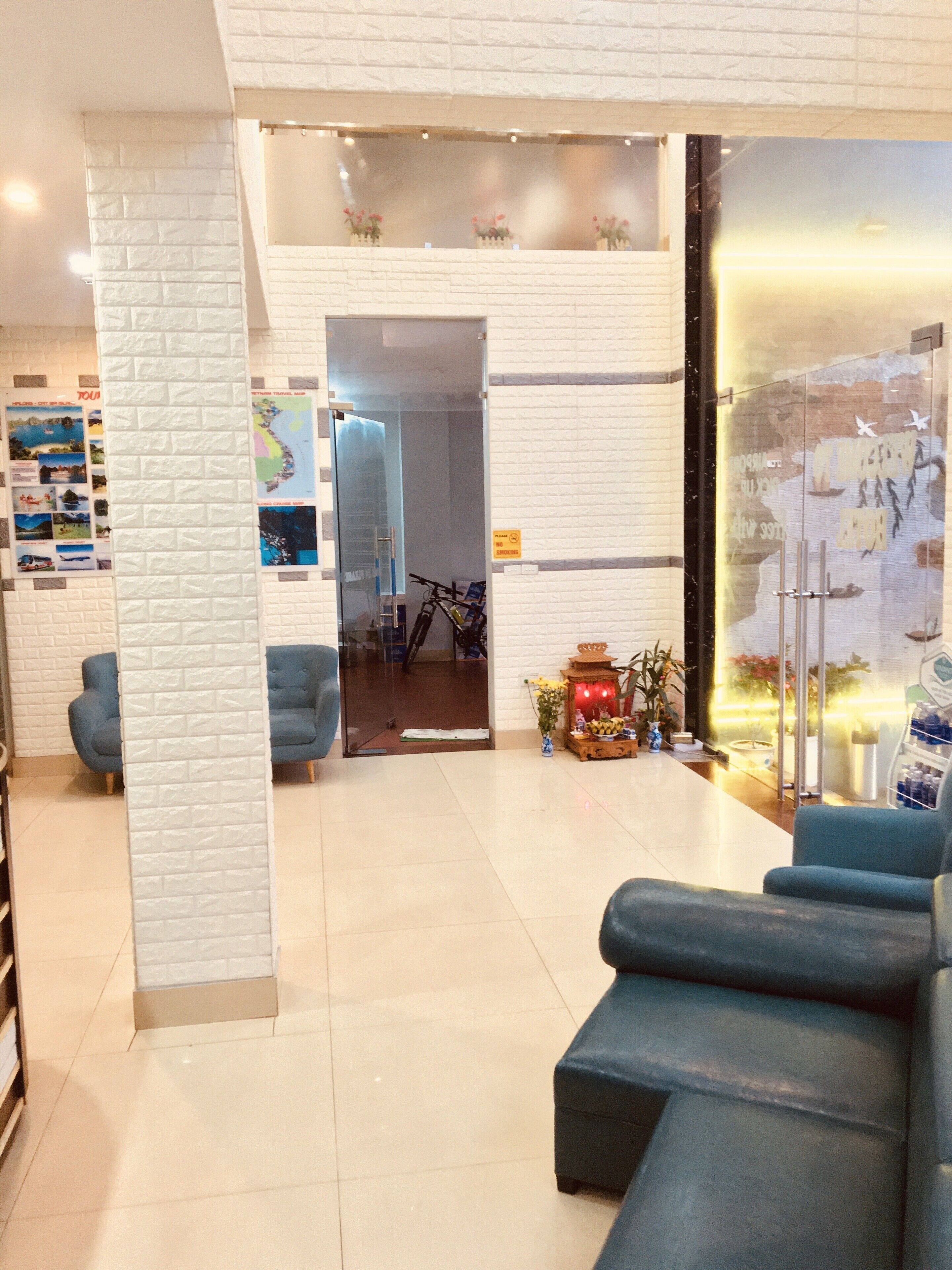 A lobby with a white brick wall, blue seating, a glass partition, and a map display.