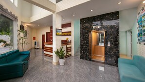 Een hotelhal met een receptiebalie, een trap en zitgedeeltes.