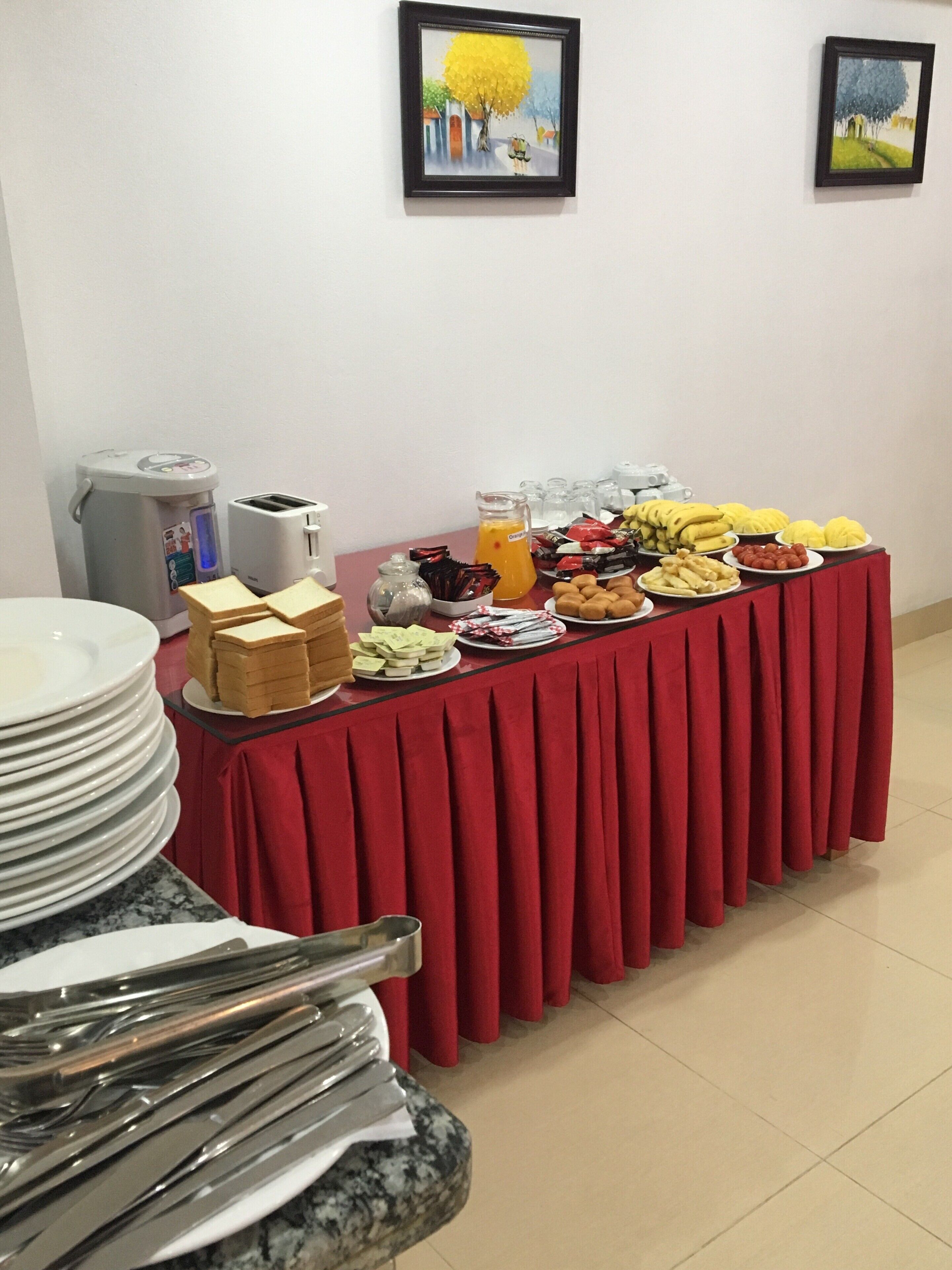 A buffet table with various food items and a stack of plates on the left.
