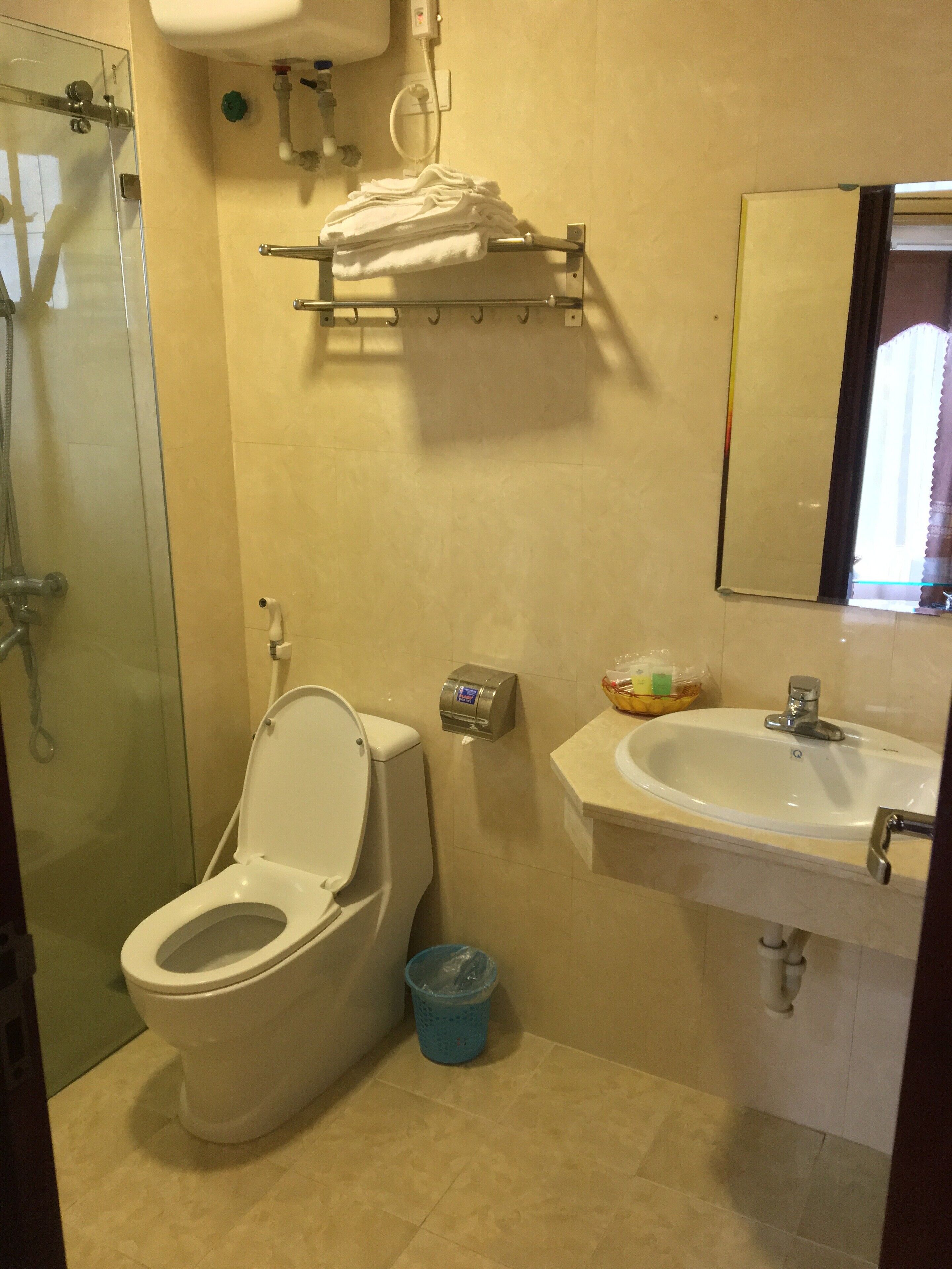 A bathroom with a toilet, a sink, a glass shower enclosure, and a towel rack.