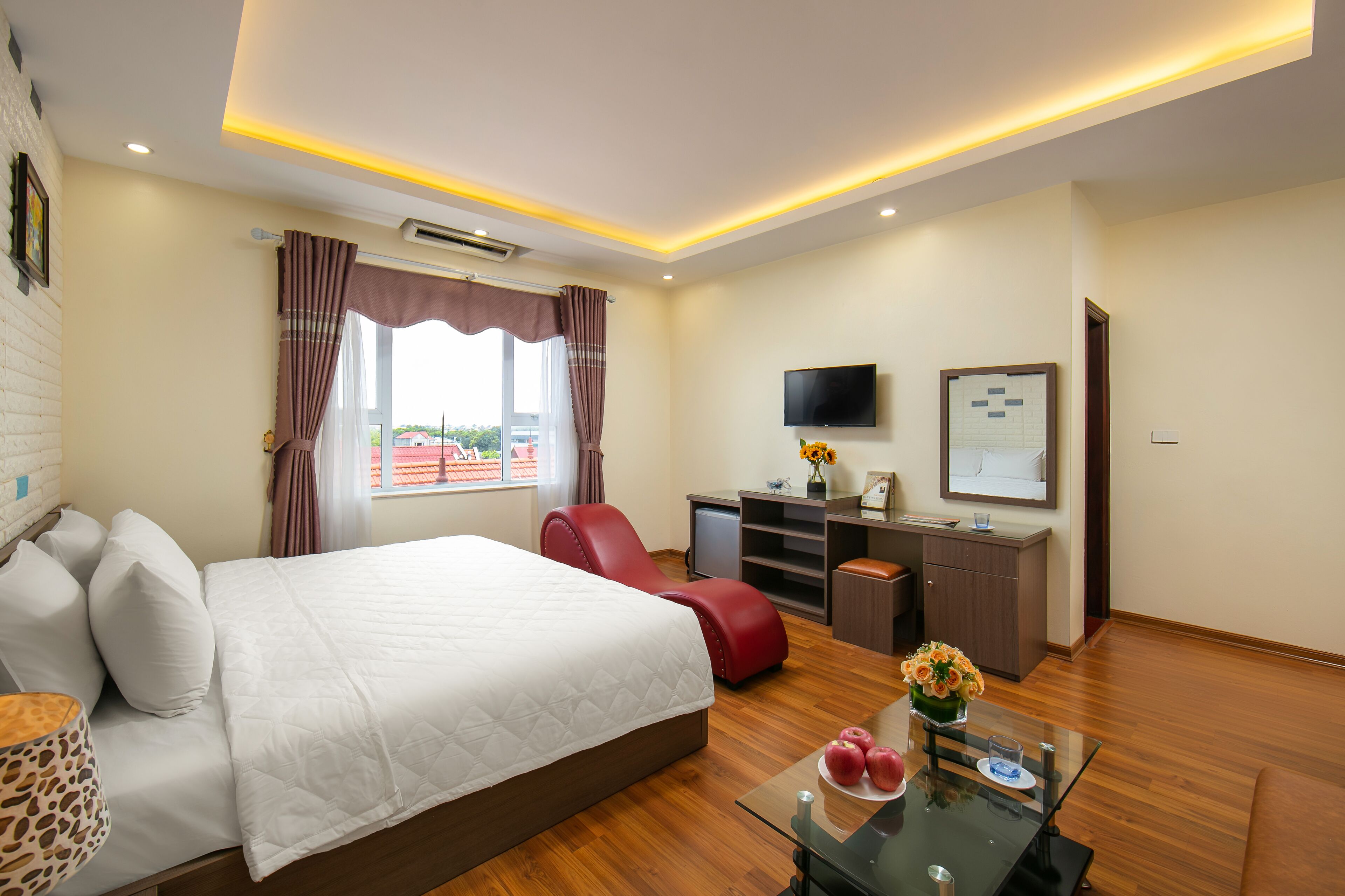 A hotel room with a bed, a desk, a TV, and a window with curtains.