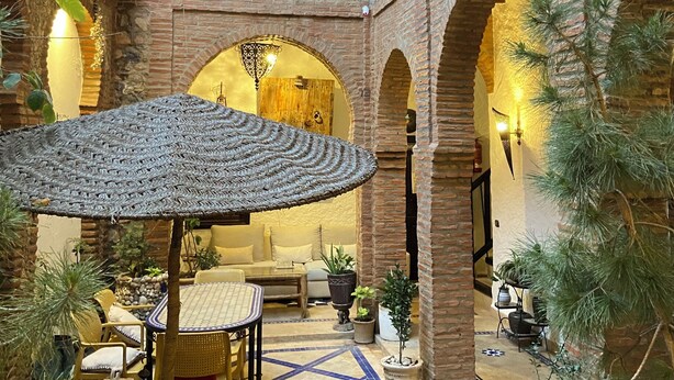 Un patio con una zona de estar central, varios arcos y plantas en macetas.