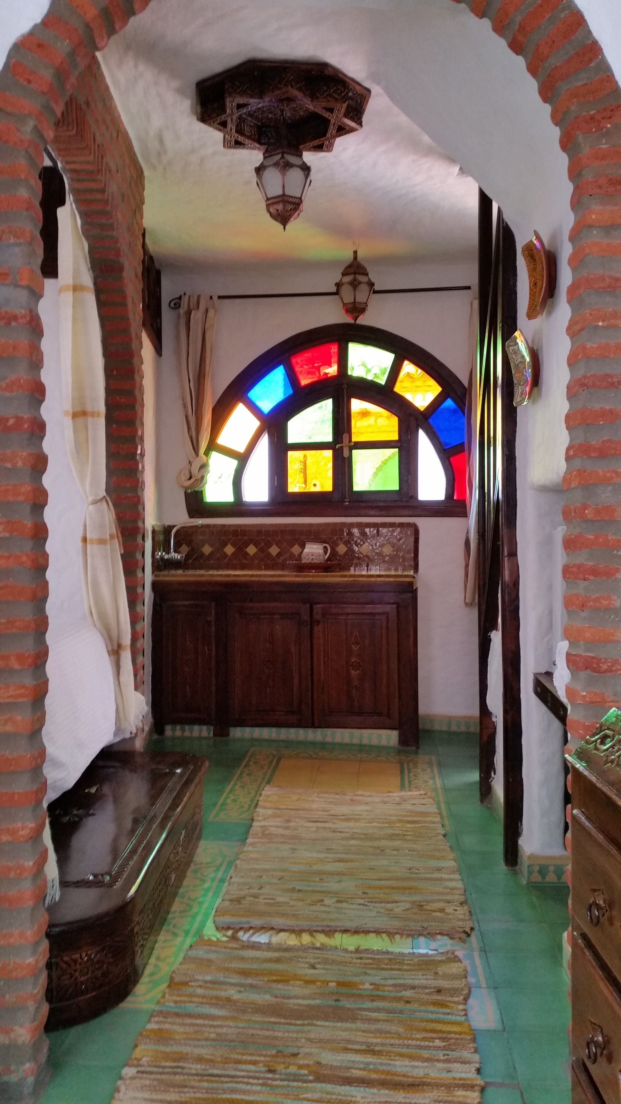 Een kamer met een houten kast, een betegelde vloer en een glas-in-loodraam.