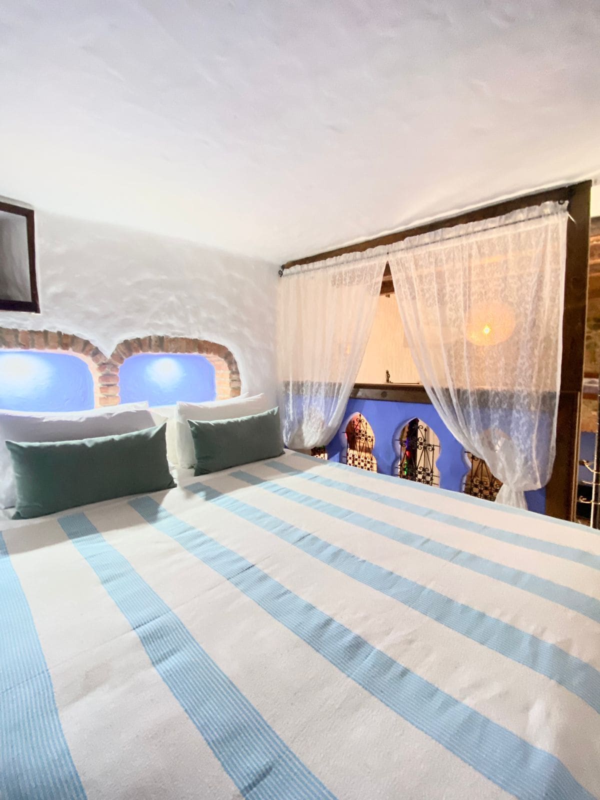 A bedroom with a large bed, a window with a view, and a decorative wall.