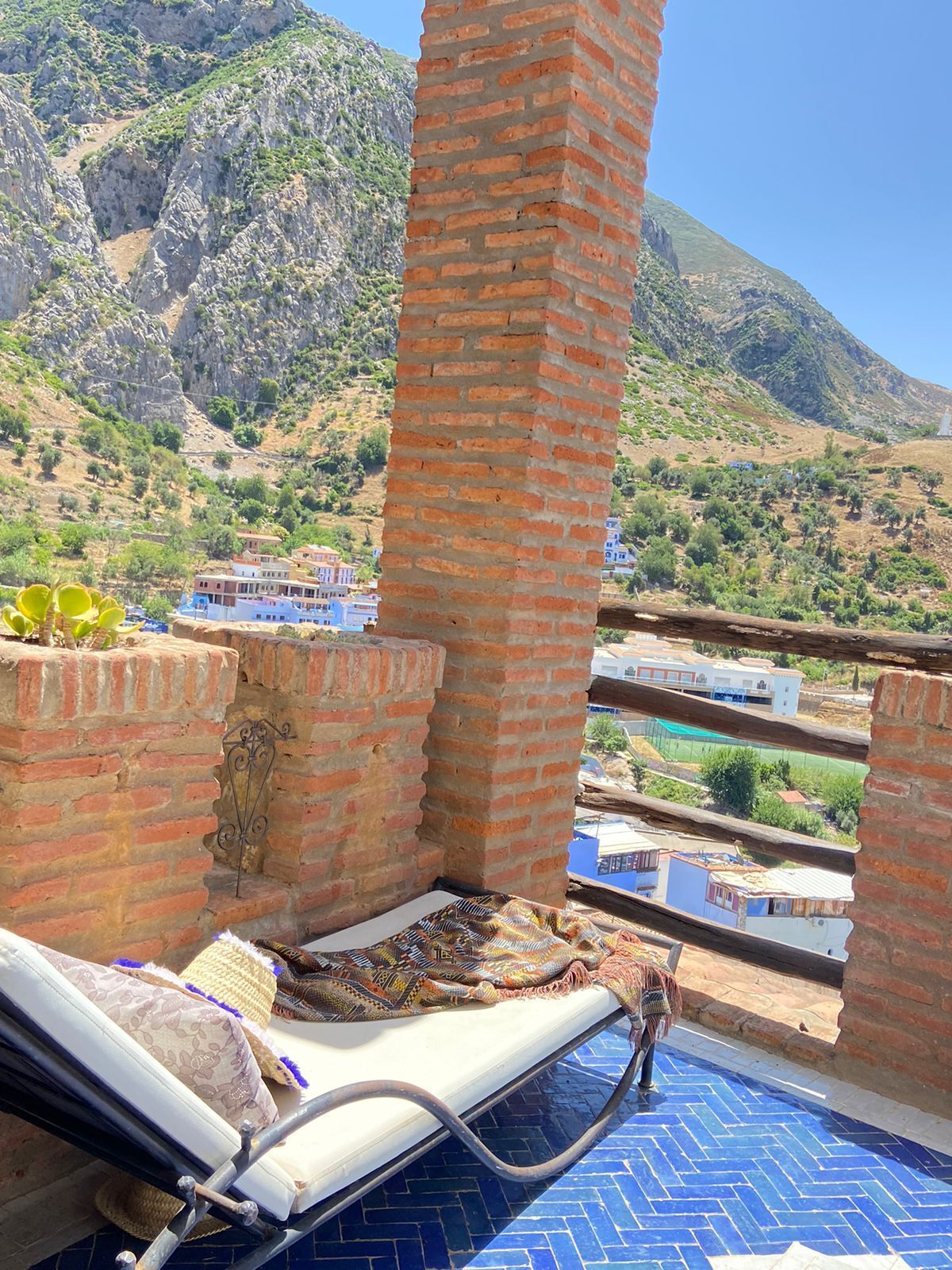 A balcony with a pool, brick walls, and a view of a mountainous landscape.