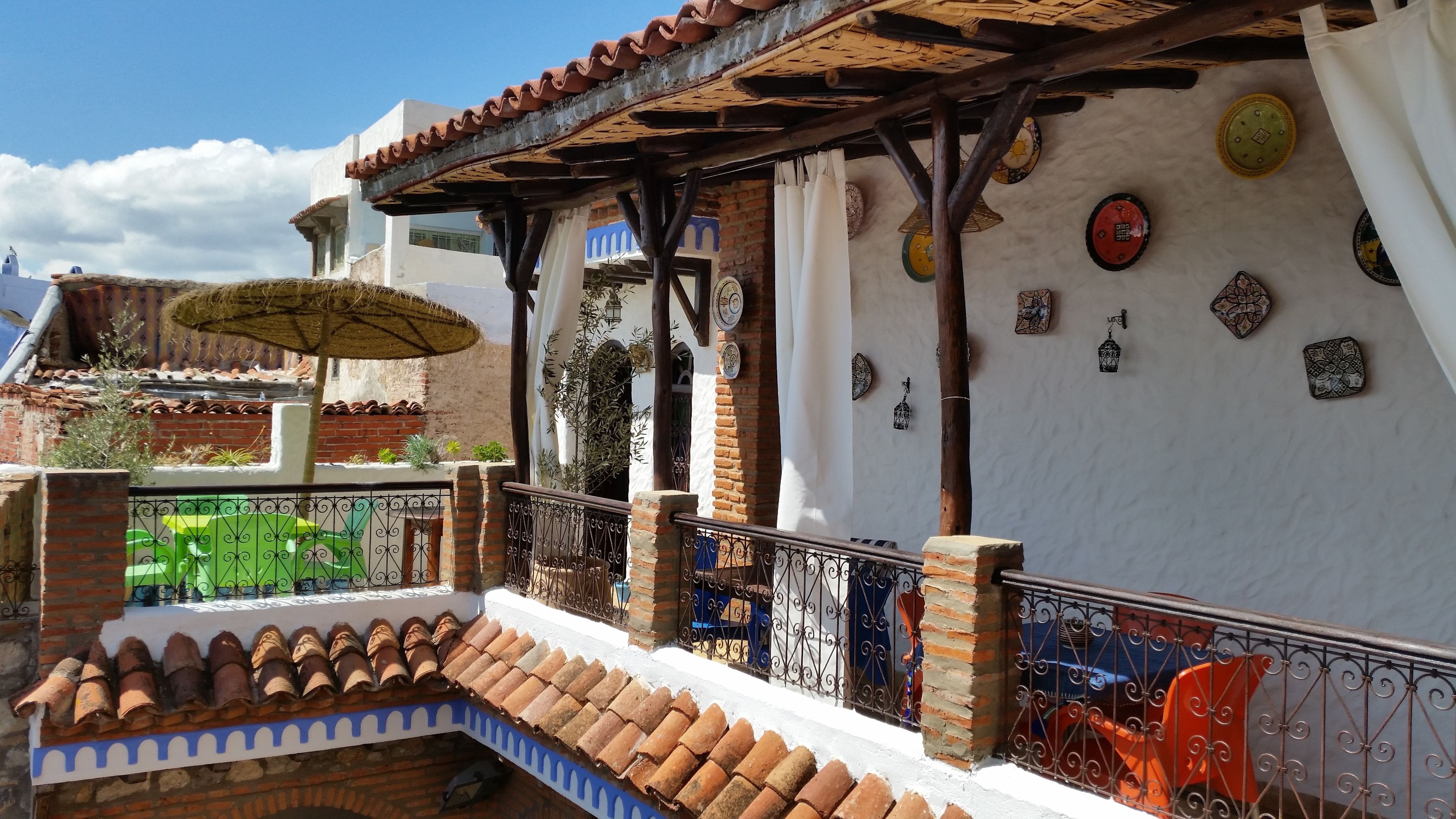 Un patio tradicional con techo de tejas, zona de estar cubierta y placas decorativas en las paredes.