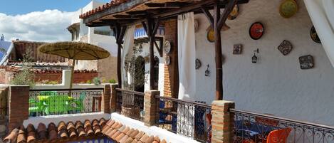 Un patio tradicional con techo de tejas, zona de estar cubierta y placas decorativas en las paredes.