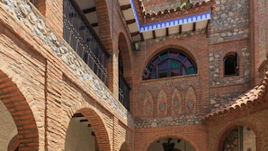 Un patio con arcos de ladrillo, plantas en macetas y suelo de baldosas.