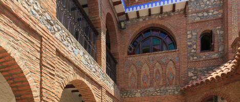 A courtyard with brick arches, potted plants, and a tiled floor.