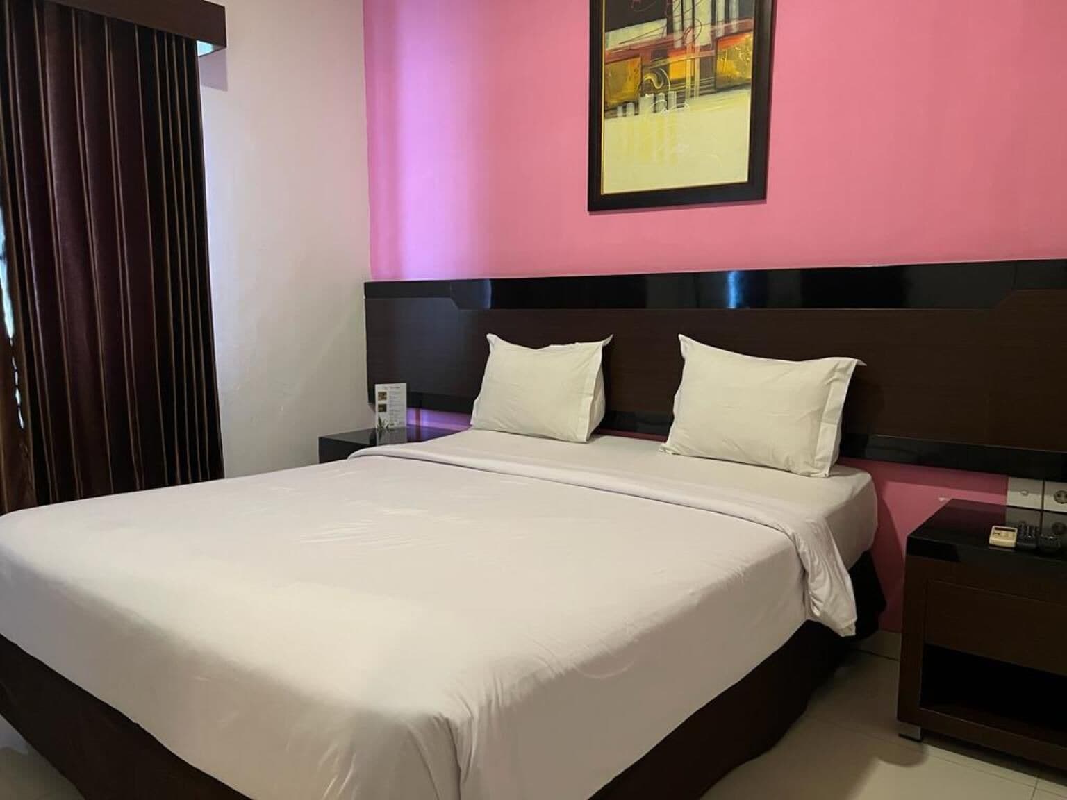 Una habitación de hotel con una cama grande, una mesita de noche, una lámpara y un cuadro en la pared.