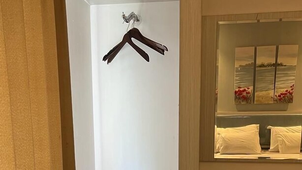A hotel room with a white wardrobe, a mirror, and a shelf with shoes. - Ayla City Hotel (Sorong)