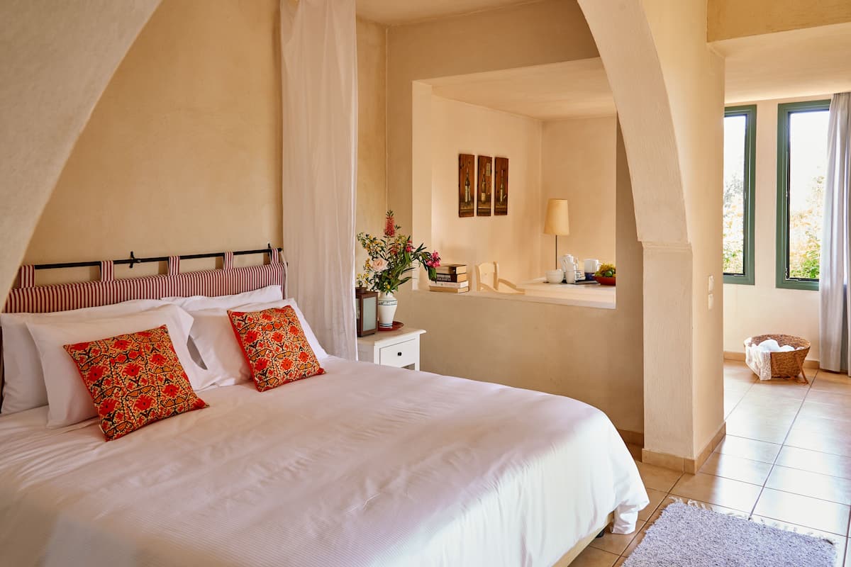 A bedroom with a large bed, a nightstand, a window, and a view of the outside.