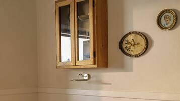 A dining area with a wooden table and chairs, a checkered floor, a cabinet with glass doors, and wall-mounted plates.