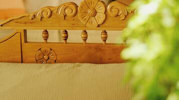 A wooden headboard with intricate carvings, a beige upholstered headboard, and a bedside table with a glass vase and a book.