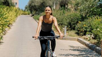 Una persona anant en bicicleta per un camí asfaltat, amb vegetació a banda i banda.