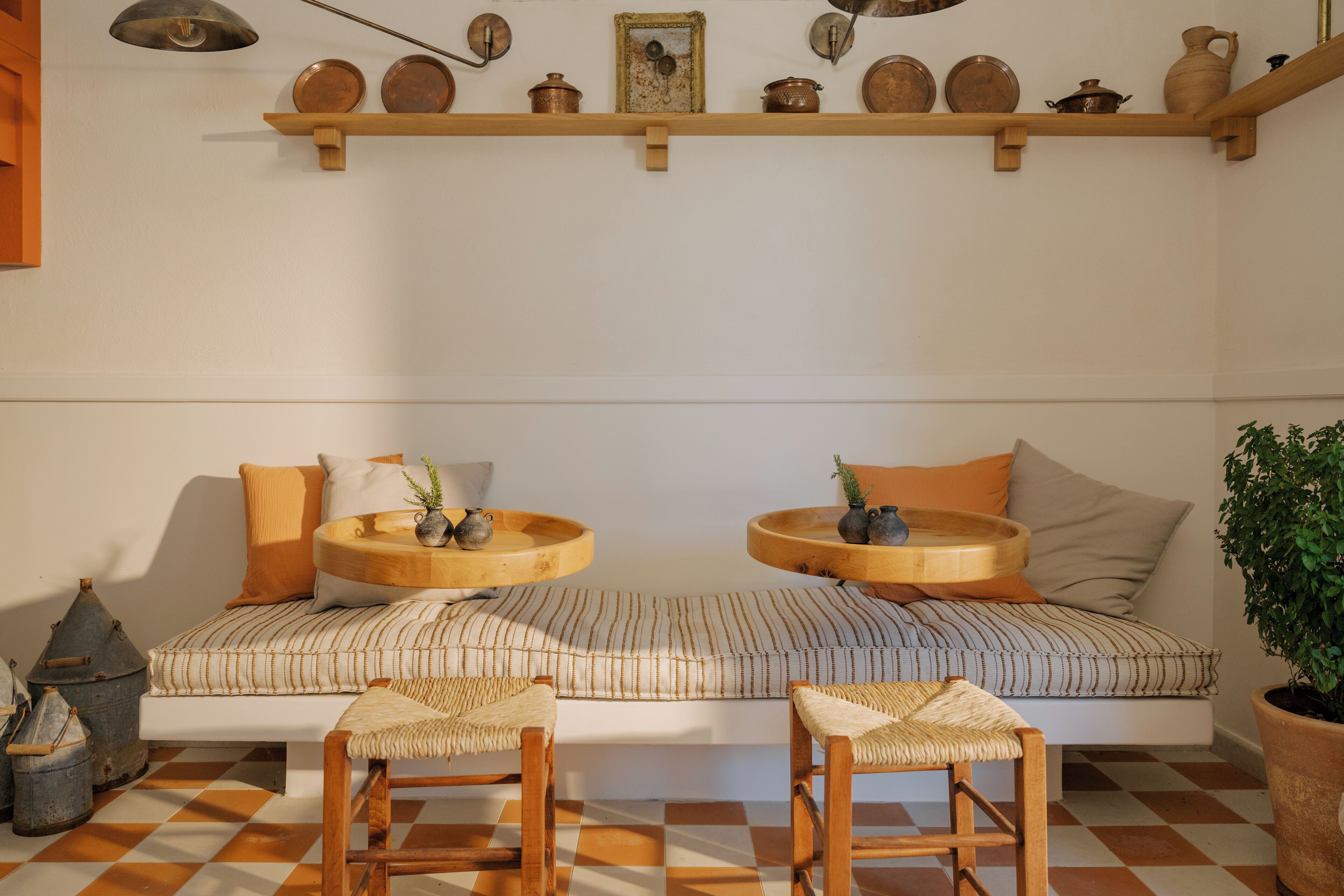 Un coin salon accueillant avec un canapé à rayures, deux petites tables en bois et un sol à carreaux.
