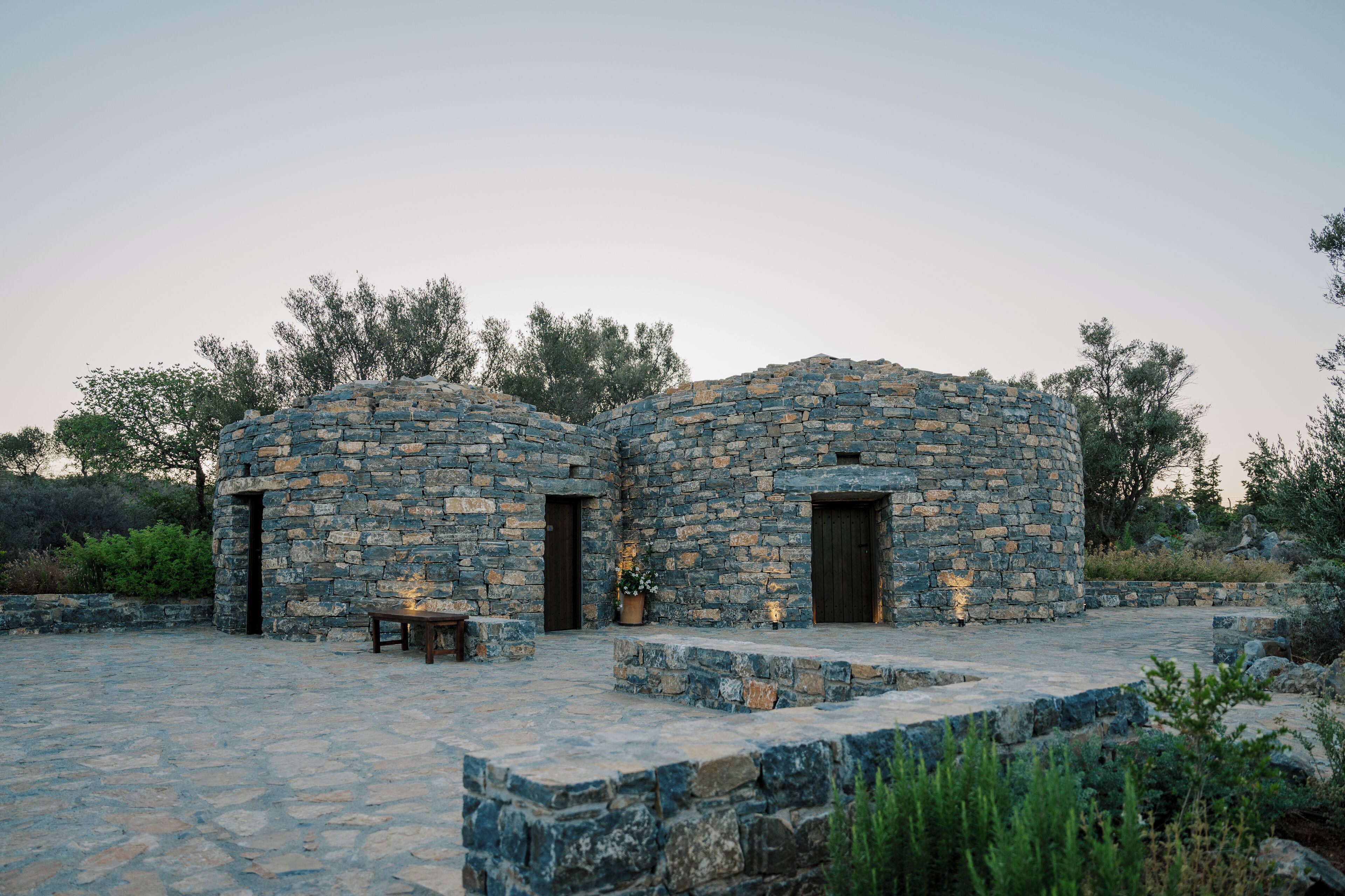 Un edificio de piedra con dos puertas y un banco en la fachada.