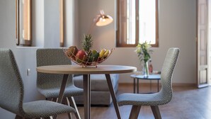 Un comedor con una mesa redonda, sillas estampadas y un frutero.