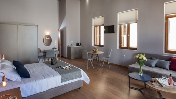Un dormitorio moderno con cama, mesita de noche y un espacio de escritorio con silla y una pequeña mesa.