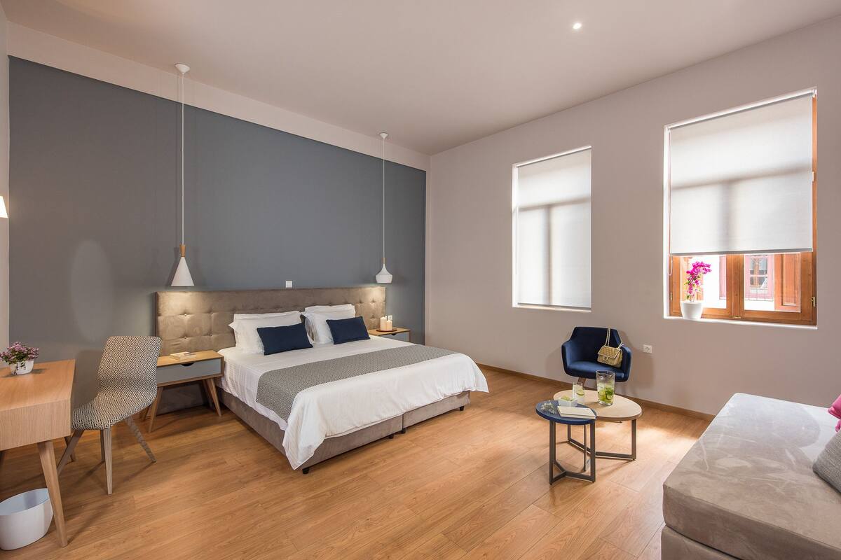 Ein modernes Hotelzimmer mit einem großen Bett, einem Schreibtisch, einem Stuhl und einem kleinen Tisch.