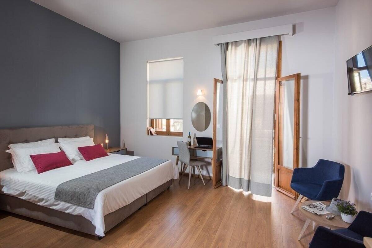 Ein modernes Hotelzimmer mit einem großen Bett, einem Schreibtisch, einem Sessel und einem Fernseher.