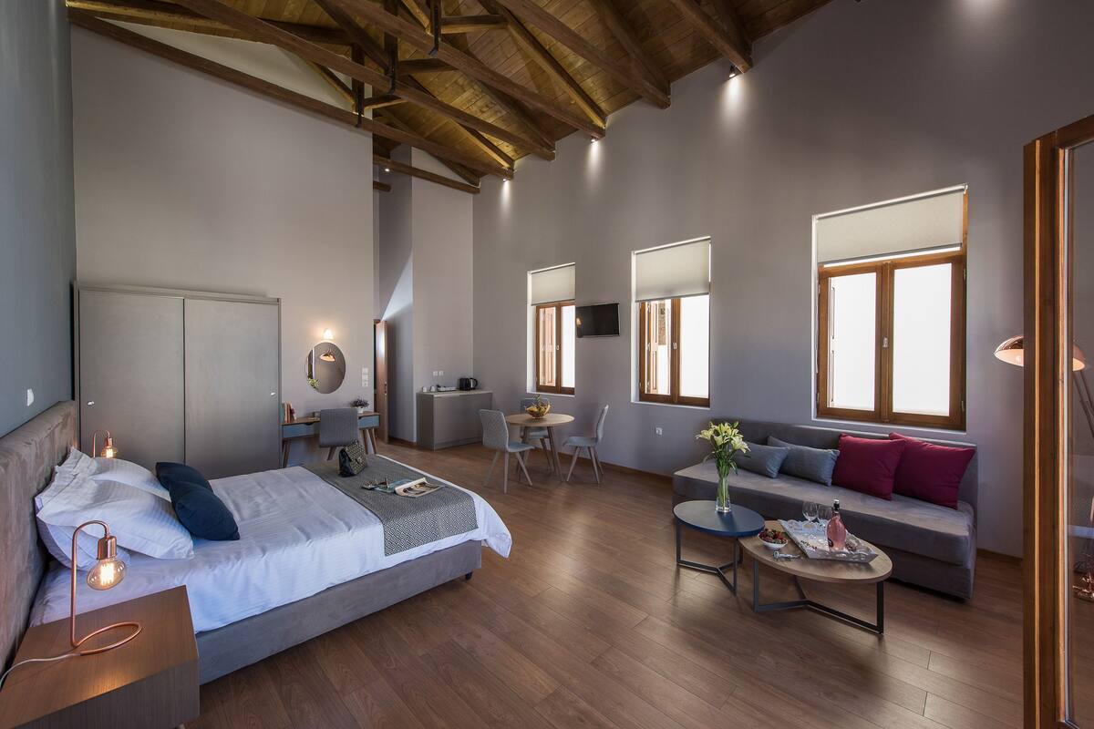 Ein modernes Hotelzimmer mit Bett, Sofa, Essbereich und Küchenzeile.