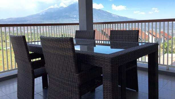 A balcony with wicker furniture and a view of a mountain. - The Villaku Batu (Batu)