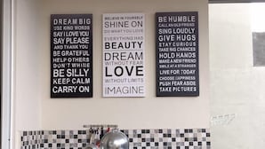 A kitchen with a checkered backsplash, a sink, and various kitchen utensils. There are three motivational posters on the wall. - The Villaku Batu (Batu)