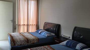 Un dormitorio con dos camas, una ventana con cortinas, una mesita de noche y un enchufe.