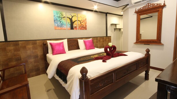 Una cama bien hecha con un tablero de cabecera decorativo, un aire acondicionado de pared y un espejo.