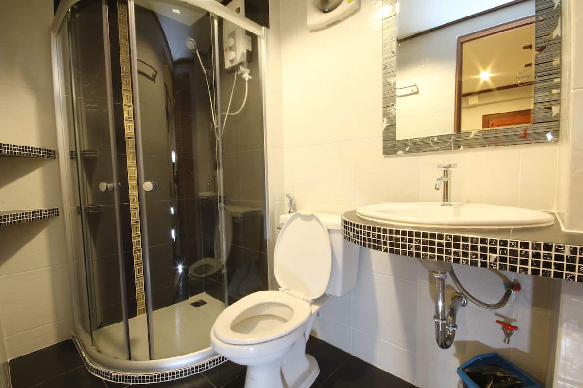 A bathroom with a glass-enclosed shower, a white toilet, and a sink with a tiled backsplash.