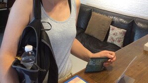 Una persona sentada a una mesa en una habitación con pared blanca y un letrero que dice "TR GUEST HOUSE".