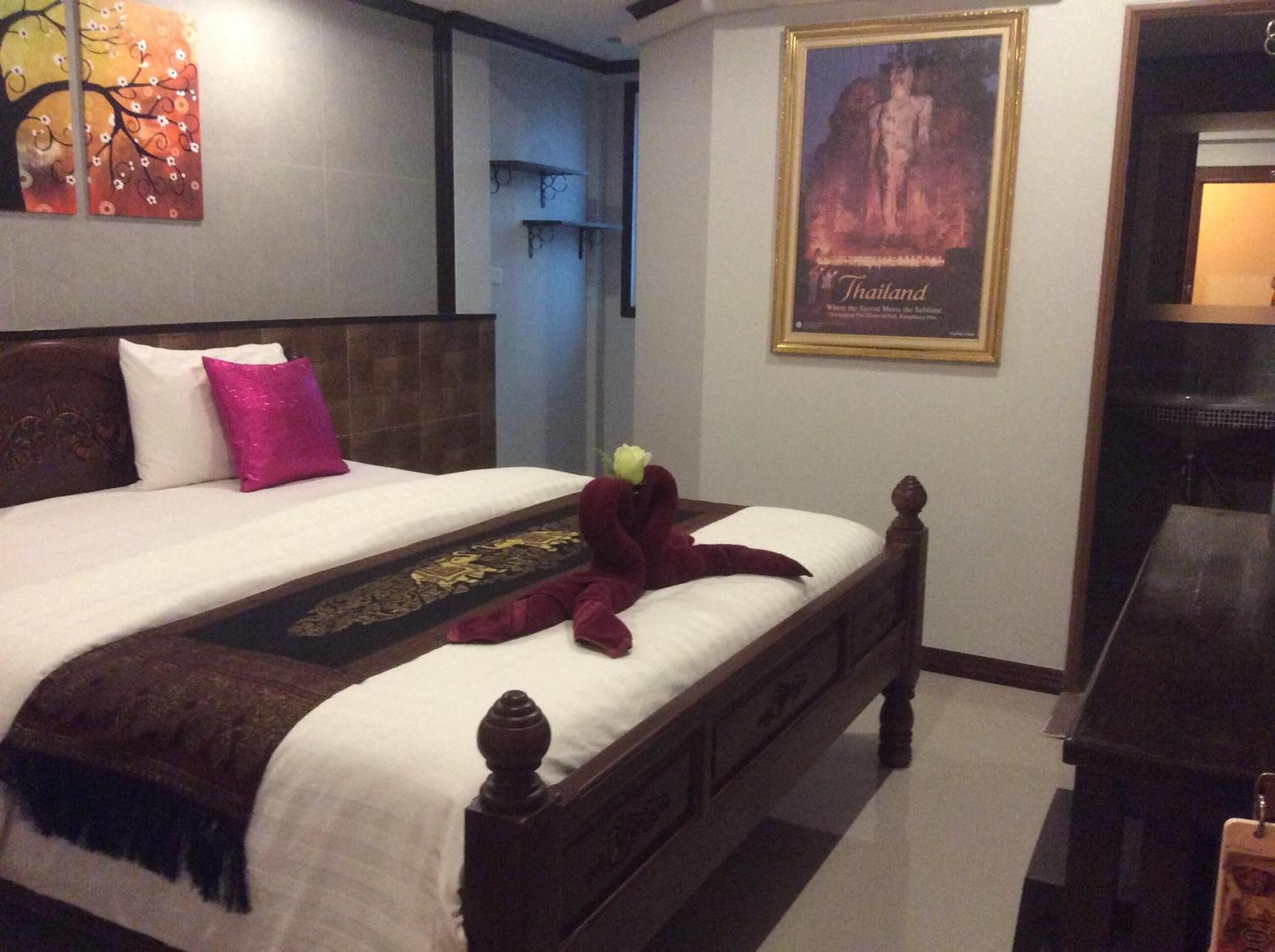 A neatly made bed with a decorative pillow, a plush toy, and a decorative item on the bedspread.