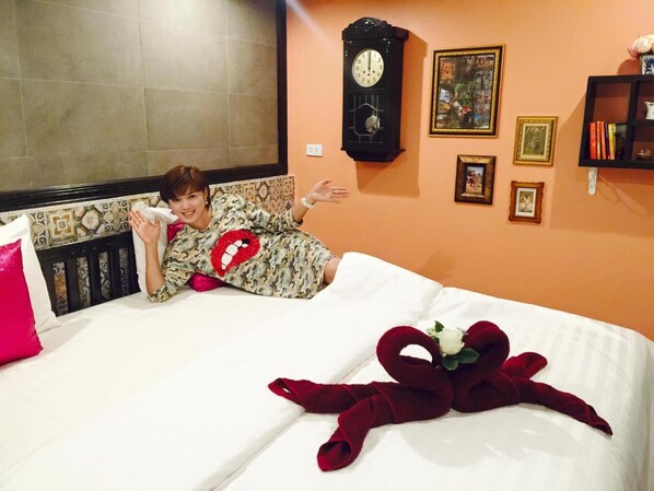 Una cama con un cojín rojo con forma de corazón, un reloj y cuadros en la pared.