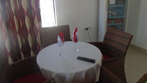 Un comedor con una mesa redonda, dos sillas, un control remoto y una botella de agua.
