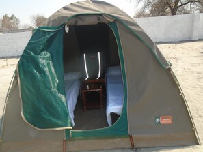 A tent with a bed and a small table inside, set on a sandy surface. - Bel Rea Guest House (Nata)