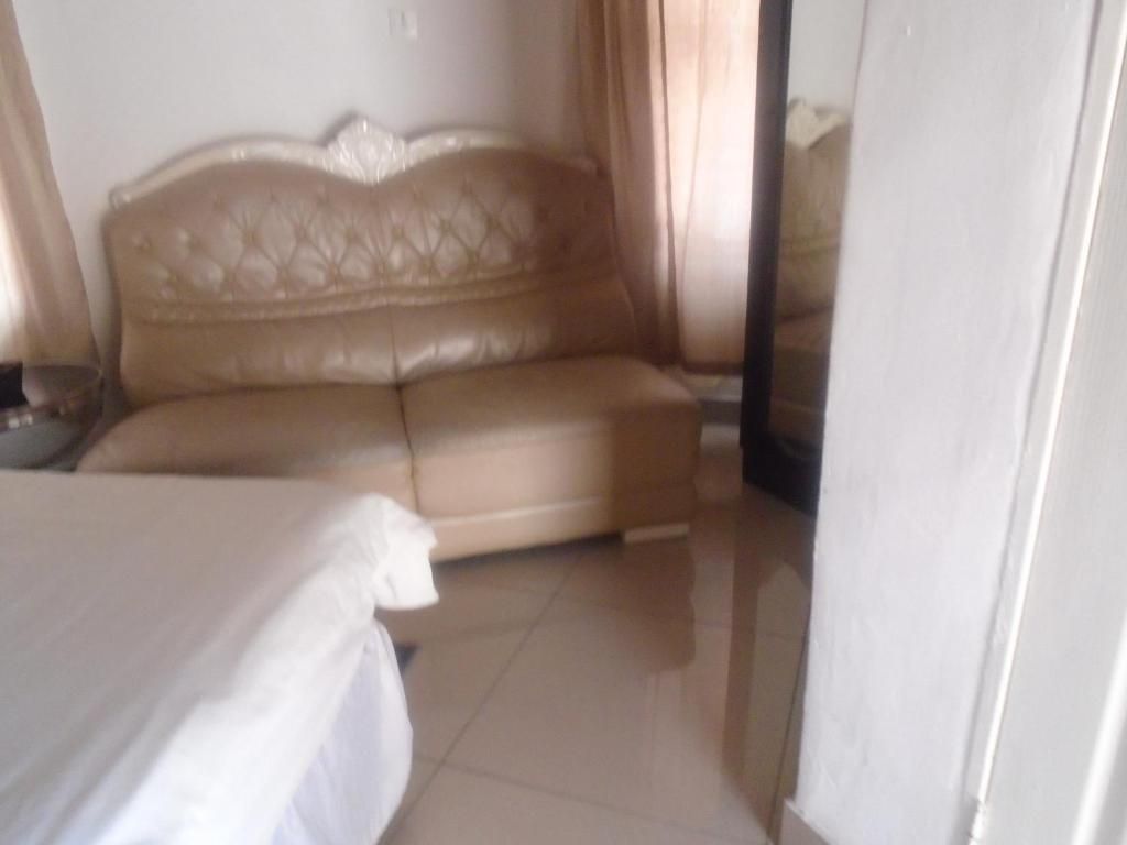 A room with a beige sofa, a bed, and a white wall.