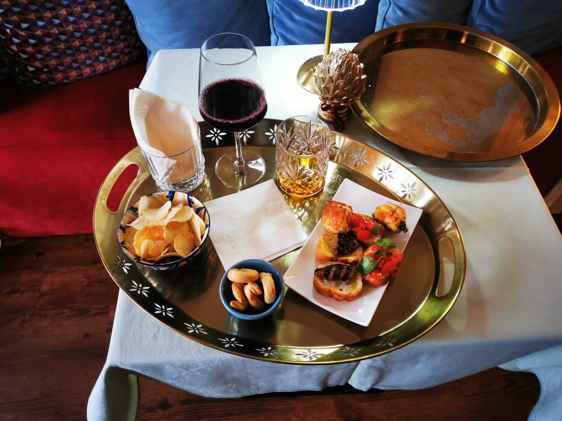 A tray with snacks, drinks, and a plate of food on a table.