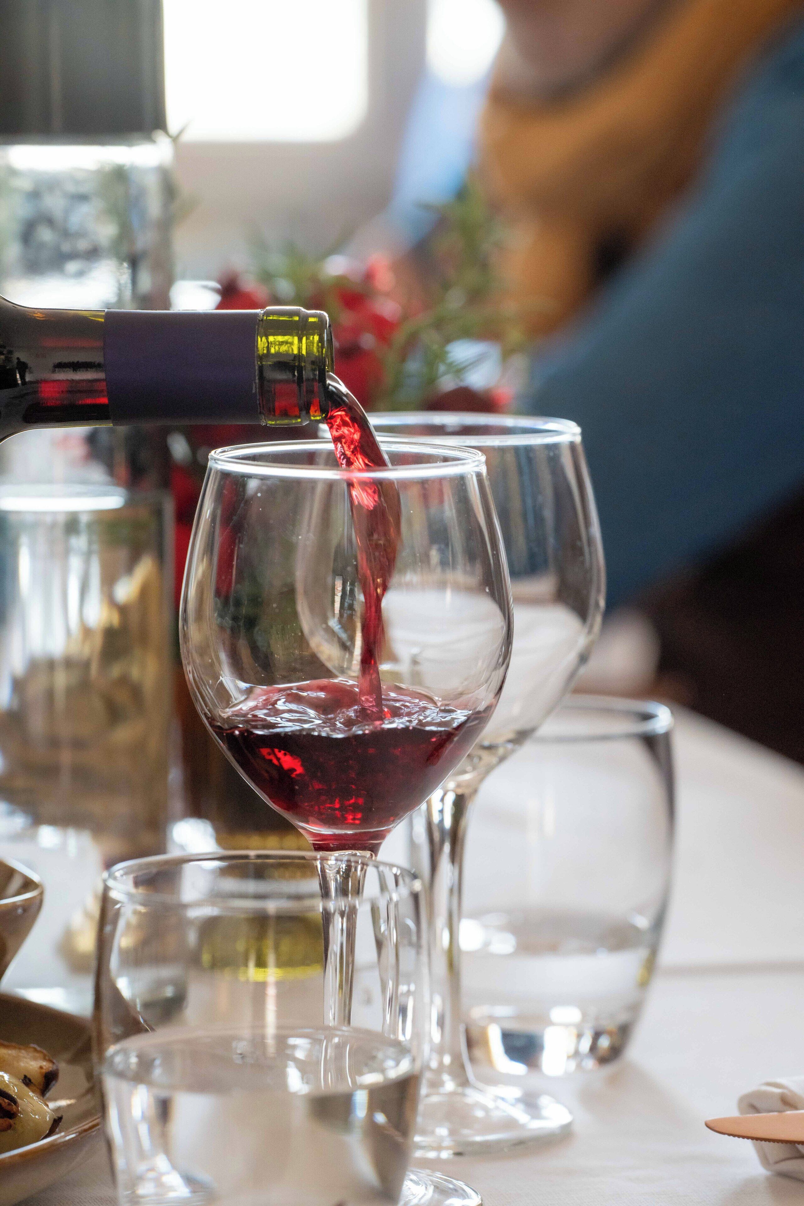 A wine bottle pouring red wine into a glass.