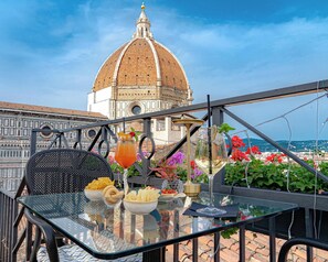 A table with food and drinks, a view of a historic building, and a clear sky. - Hotel Villani (Florence)