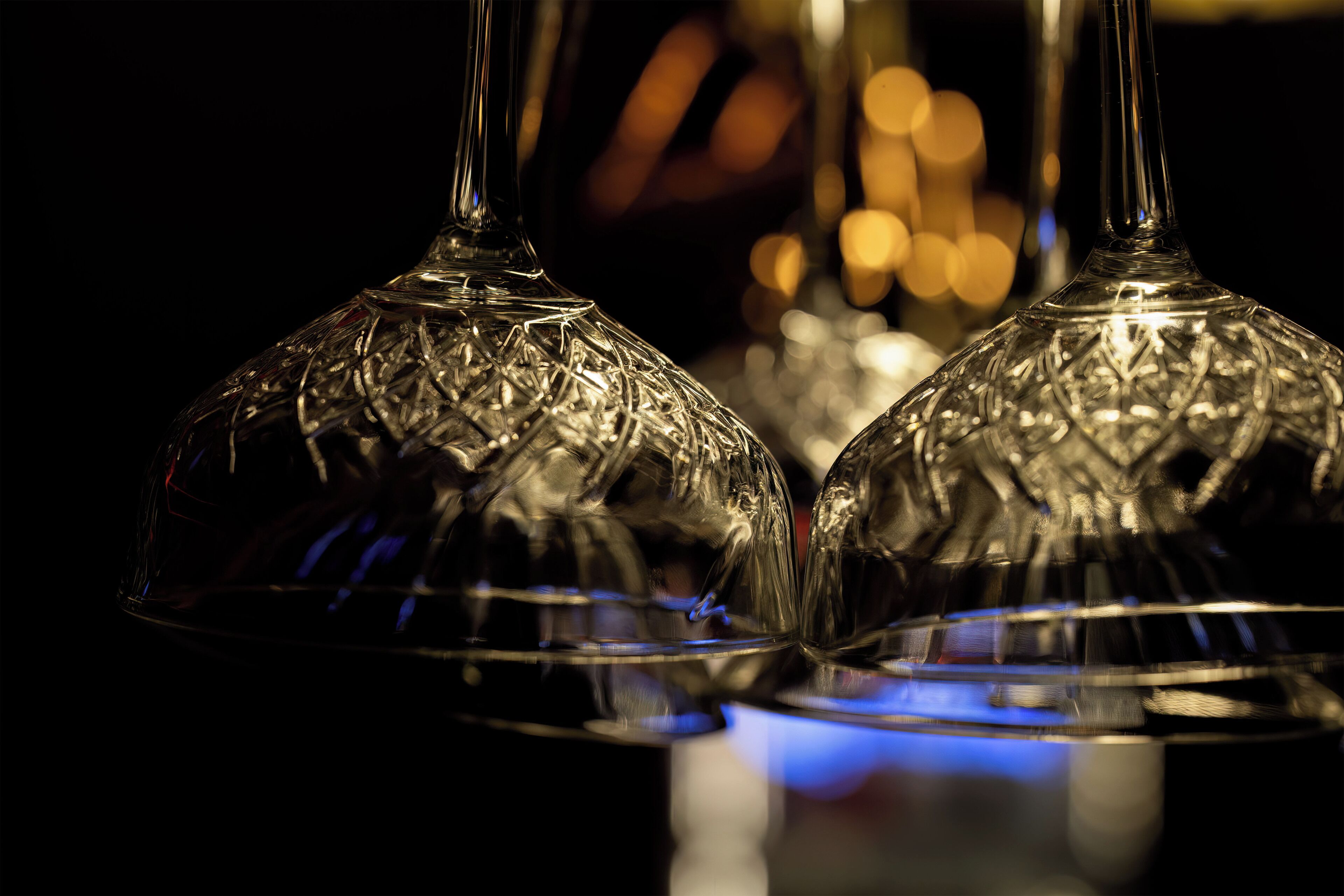 Dos copas de cristal transparente con diseños elaborados, sobre una superficie reflectante.