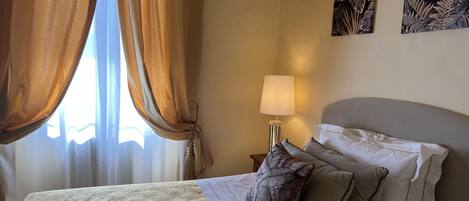 A hotel room with a bed, a nightstand, a lamp, and two wall art pieces.