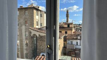 Blick durch ein Fenster auf ein Gebäude mit Ziegeldach und Steinverkleidung.